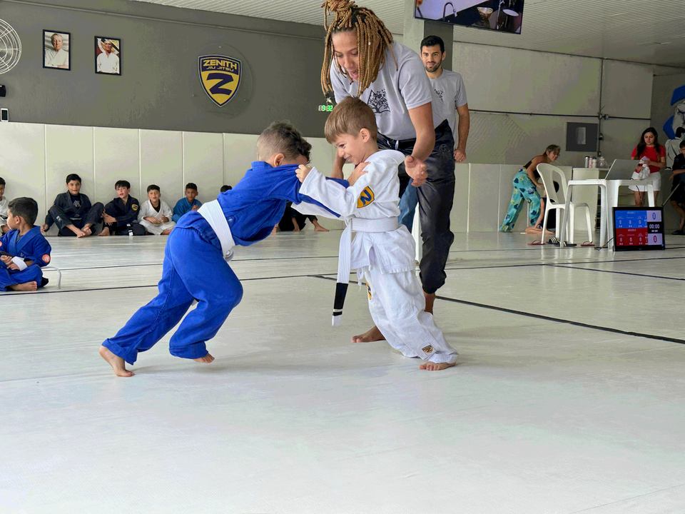 Crianças treinando jiu jitsu na Zenith, com adultos da equipe acompanhando no tatame